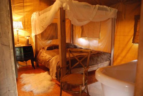 ein Schlafzimmer mit einem Himmelbett und einer Badewanne in der Unterkunft Tentes Safari aux Gîtes de Cormenin in Saint-Hilaire-sur-Puiseaux