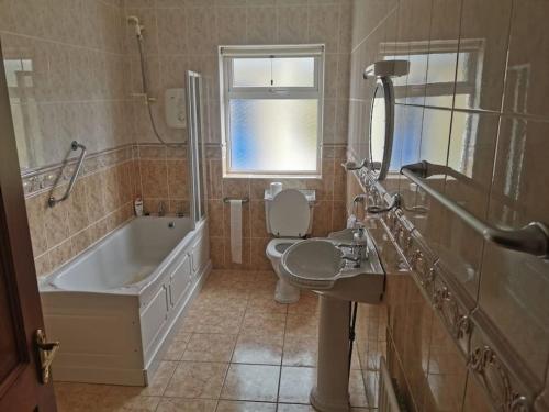 ein Badezimmer mit einer Badewanne, einem WC und einem Waschbecken in der Unterkunft Cozy 6 Bedroom house with spectacular views in Belmullet