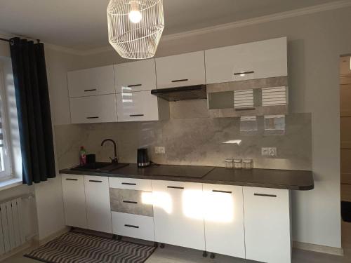 HarklowaApartament u Irenki的厨房配有白色橱柜和黑色台面