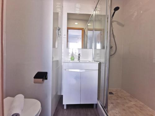 a white bathroom with a sink and a shower at Vila Alexandra in Costa da Caparica