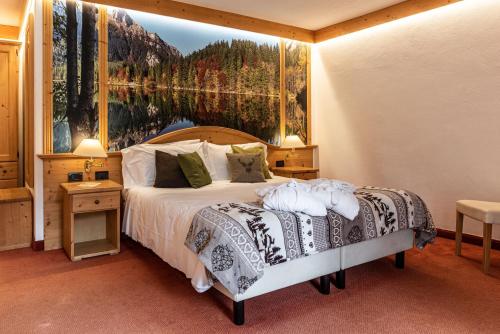a bedroom with a bed with a painting on the wall at Hotel Caminetto in Folgarida