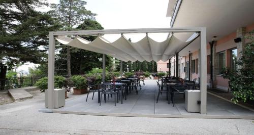 a patio with tables and chairs under a white canopy at Best Western Hotel I Colli in Macerata