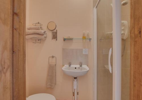 La salle de bains blanche est pourvue d'un lavabo et d'une douche. dans l'établissement Piglet Cottage, à Seamer