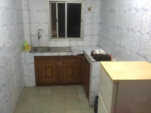 Una pequeña cocina con fregadero y ventana. en Chambre Securisée centre Dakar, en Dakar