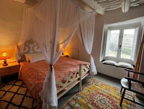 a bedroom with a canopy bed and a window at Casa Carmela, rural house with spectacular views, in an exquisite area in Atalbéitar