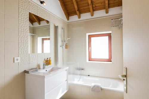 La salle de bains est pourvue d'un lavabo, d'une baignoire et d'un miroir. dans l'établissement Les Jardins de la Villa d'Olne, à Spa