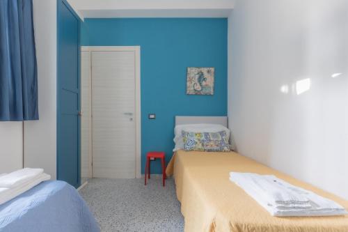 a room with two beds and a blue wall at La Scala Suite in Realmonte