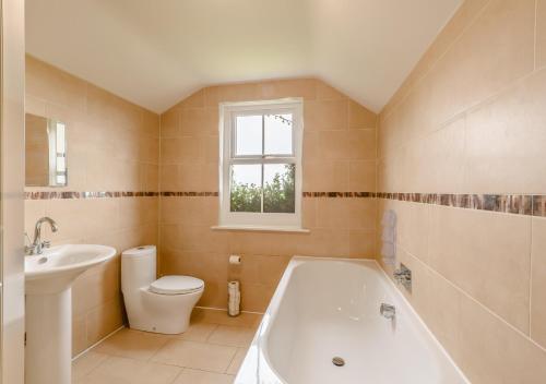 a bathroom with a tub and a toilet and a sink at Vale View in Glanton