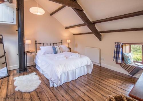 Akeld的住宿－Homildon Cottage，铺有木地板的客房设有一间带大床的卧室
