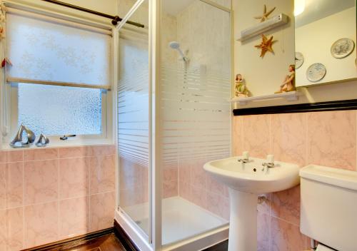 uma casa de banho com um chuveiro, um lavatório e um WC. em Dunes Reach 3 Dunes Court em Beadnell