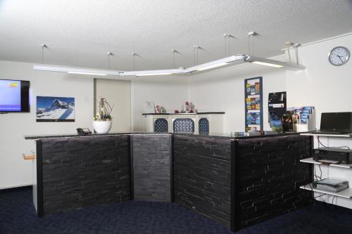 an office with a black counter with a clock on the wall at Hotel Crystal Interlaken in Interlaken