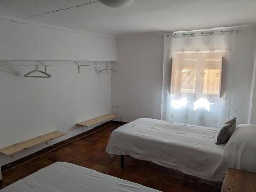 Habitación blanca con 2 camas y ventana en Casa Malena - Biar, en Biar