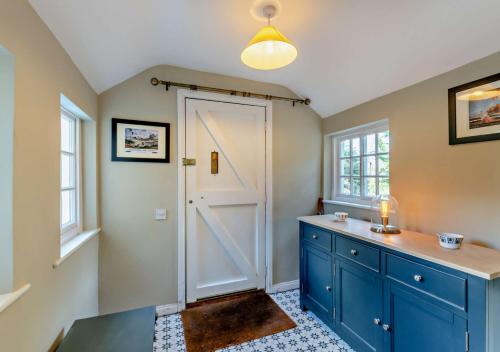 a bathroom with a blue cabinet and a door at Glebe Farmhouse in Ellingham