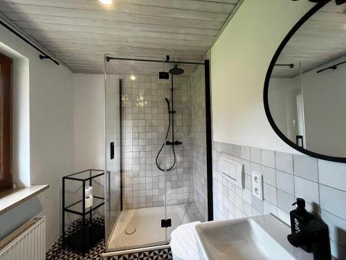Alpen Lodge in Osterhofen - Berge, Ruhe & Natur في بايريشزيل: حمام مع حوض استحمام ودش مع مرآة