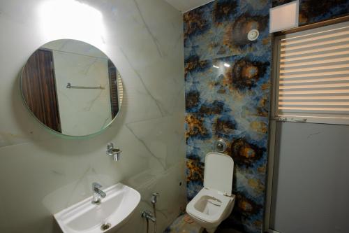 y baño con lavabo, espejo y aseo. en Covie Kharghar 200, en Navi Mumbai