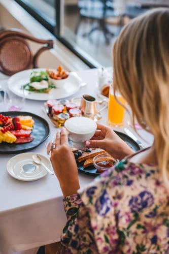 a woman sitting at a table with a plate of food at Esplanade Zagreb Hotel in Zagreb