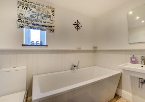 a white bathroom with a tub and a sink at Pegasus Cottage in Craster