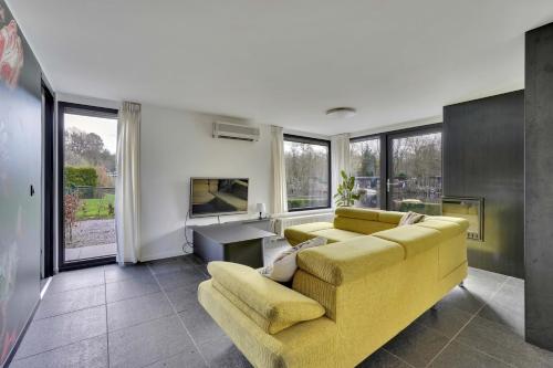 ein Wohnzimmer mit einem gelben Sofa und einem TV in der Unterkunft Vijverzicht in Lanaken