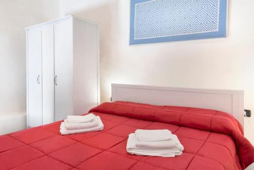 Una cama roja con dos toallas encima. en Sorres Home & Relax 10 min da Sassari Loft AC e WiFi, en Codrongianos