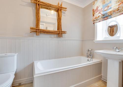a white bathroom with a tub and a sink at The Boat House in Bamburgh