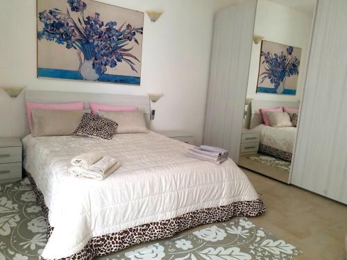 1 dormitorio con 1 cama grande y espejo en Casa vacanze con giardino e area barbecue, en Martis