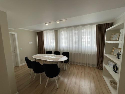 a dining room with a white table and black chairs at Apartament 1 Lalelelor in Năsăud