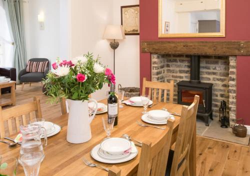 una sala da pranzo con tavolo in legno e camino di The Greenhouse a Bamburgh