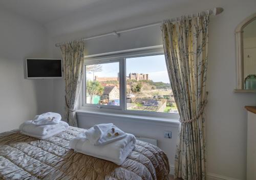 a bedroom with towels on a bed in front of a window at Finn Cottage in Bamburgh