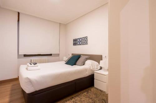 a bedroom with a large bed and a night stand at Apartamento en la Ribera Bilbao Anfitrión Verónica in Bilbao