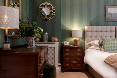 a bedroom with a bed and a dresser with a lamp at Burleigh Court Hotel in Stroud