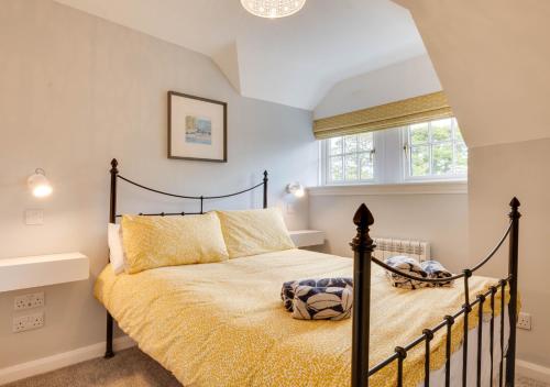 a bedroom with a black bed with yellow sheets and a window at The Shambles in Beadnell