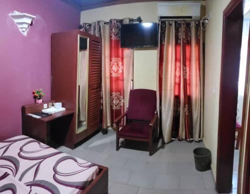 a bedroom with a bed and a chair and a mirror at Appart'hotel britannia in Yaoundé