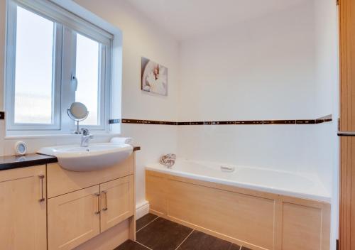 a bathroom with a sink and a tub and a mirror at Twin Palms No 2 in North Sunderland