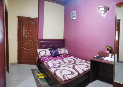 a bedroom with a bed with a purple wall at Appart'hotel britannia in Yaoundé