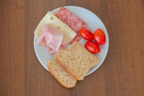 a plate of food with meats and cheese and tomatoes at Hotel Casa Adolfo Ischia in Ischia