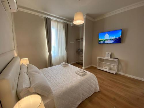 a bedroom with a white bed and a flat screen tv at FOUR LIONS VILLA GUESTHOUSE in Pisa