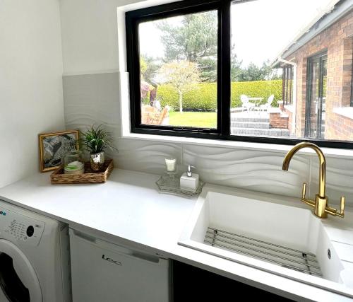 a white kitchen with a sink and a window at Fairways Villa Newcastle in Newcastle