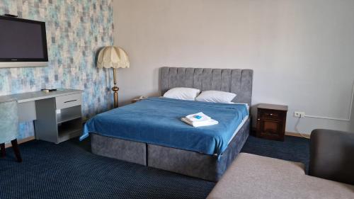 um quarto de hotel com uma cama, uma secretária e uma televisão em Victoria Hotel em Aktau