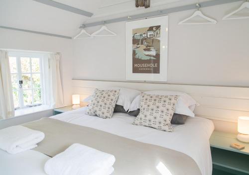 a bedroom with a large bed with two pillows at Molly Muppet in Mousehole