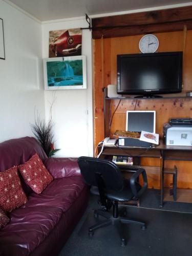a living room with a couch and a desk with a tv at Mablet Family Home Stay in Auckland