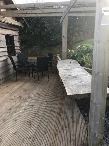 un patio con mesa y sillas en una terraza de madera en Bryn Fach Log Cabin en Merthyr Cynog