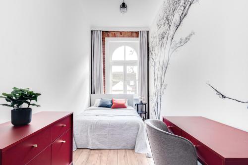 - une chambre avec un lit, une commode rouge et une fenêtre dans l'établissement Apartament Plac Jana Pawła 7 Centrum Wrocław, à Wrocław