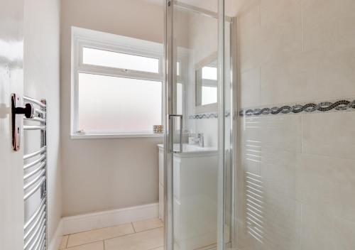 a glass shower in a bathroom with a window at Sandy Dell in Beadnell