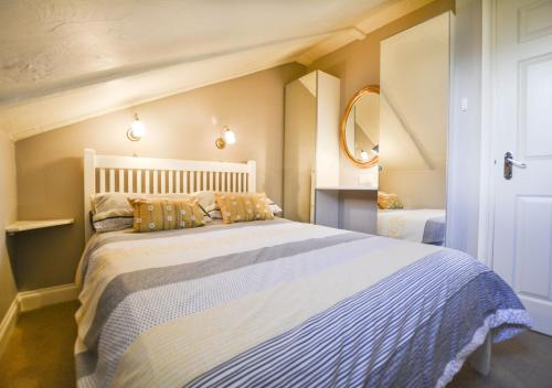 a bedroom with a large white bed and a mirror at Larch Cottage in Craster