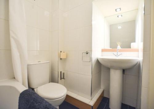 a white bathroom with a toilet and a sink at Larch Cottage in Craster