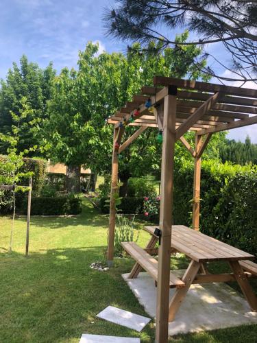 una pérgola de madera y un banco de madera en un patio en Chambre d'Hôtes Les Bacquerins en Sainte-Hélène