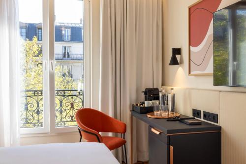 a hotel room with a bed and a chair and a window at Alberte Hôtel in Paris