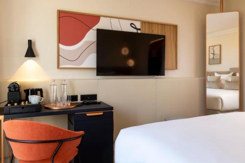 a hotel room with a bed and a desk and a tv at Alberte Hôtel in Paris