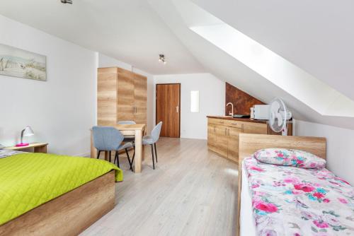 1 dormitorio con cama, escritorio y mesa en Malta apartamenty i pokoje, en Karwia