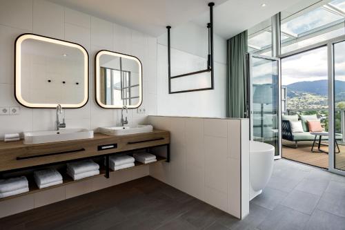 a bathroom with two sinks and a large mirror at Four Points by Sheraton Panoramahaus Dornbirn in Dornbirn